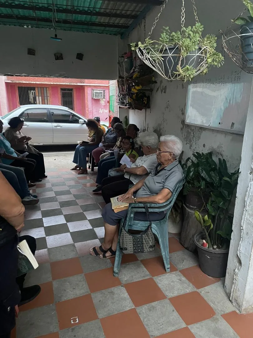 Comunidad reunida en semicírculo en el zaguán de una casa