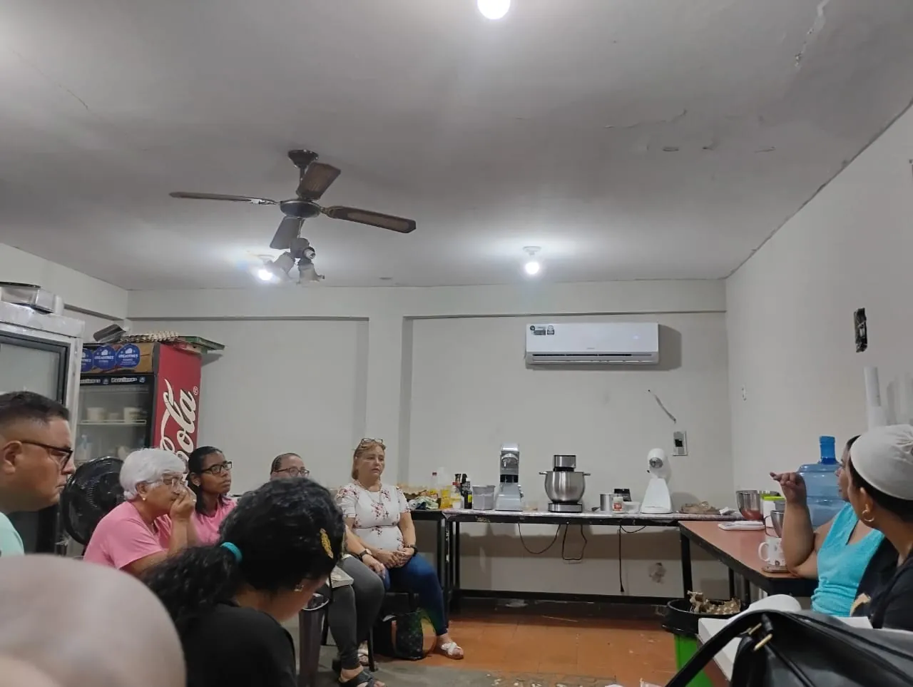 Comunidad sentada en círculo dentro de un local, con el ventilador encendido