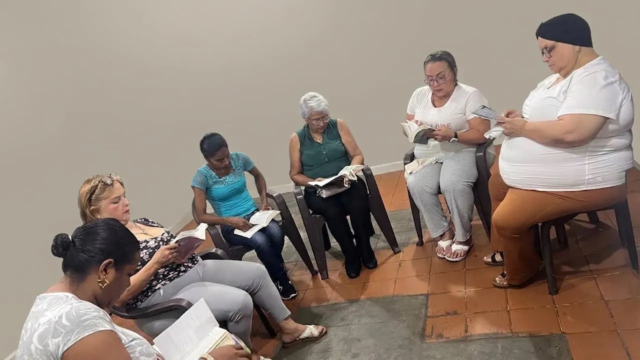 Mujeres de una comunidad leyendo sus hojas sentadas en semicírculo