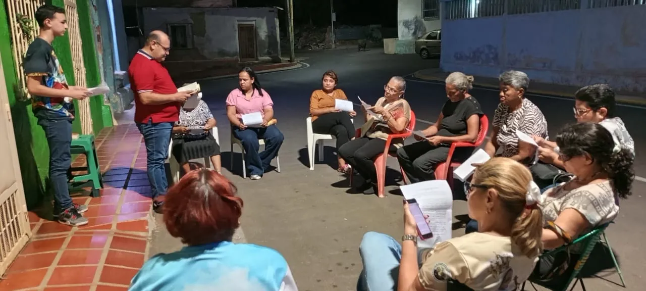 Comunidad reunida de noche en la calle, en círculo, leyendo la Palabra